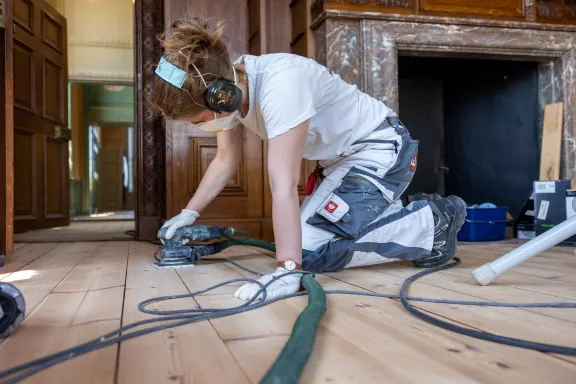 De houten vloer van de lege vertrekken worden geschuurd