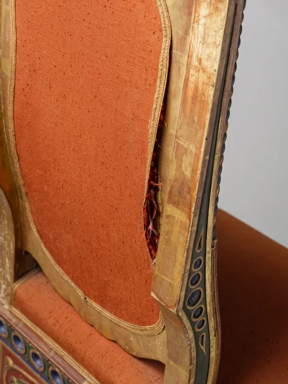 Detail van een Moorse stoel van de achterkant met hout en vergulding met ontbrekende stukjes van de gelijmde, houtgesneden decoraties, van de afwerklaag en schade aan de poten.