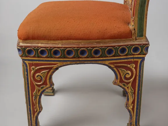 Detail van een Moorse stoel van de zijkant met hout en vergulding met ontbrekende stukjes van de gelijmde, houtgesneden decoraties, van de afwerklaag en schade aan de poten.