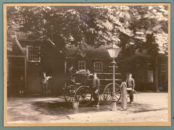 Historische sepia foto waarbij een rijtuig schoongemaakt wordt door mannen in uniform