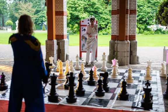 Twee bezoekers spelen buiten schaken met grote schaakstukken