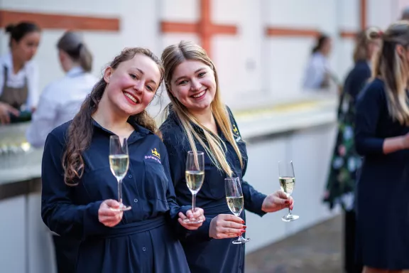 Twee horecamedewerkers delen glazen bubbels uit