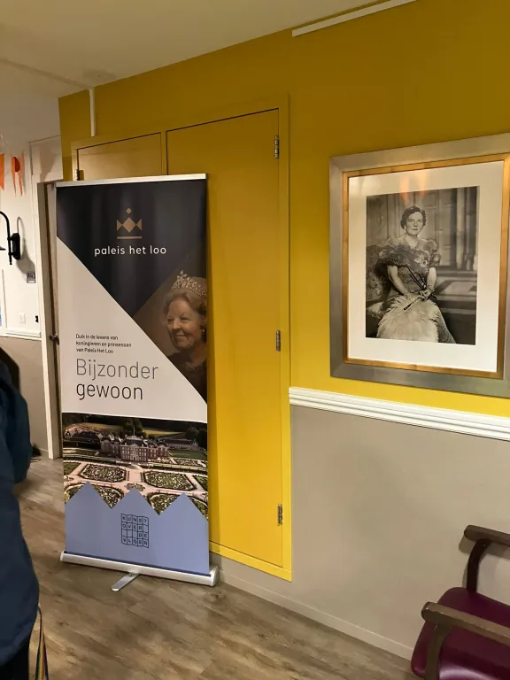 banner met promotie voor tentoonstelling Bijzonder Gewoon voor een gele muur met foto van Juliana