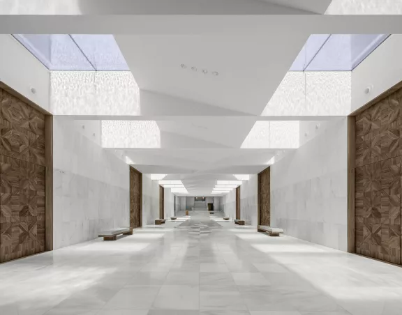 Grand foyer with light on the marble walls and floors and the wooden doors with floral motif