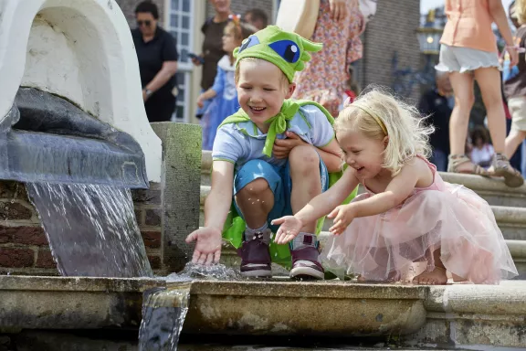 Kinderen verkleed als prins en prinses spelen met de fontein