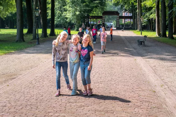 Scholieren lopen lachend over de stallenlaan naar Paleis Het Loo