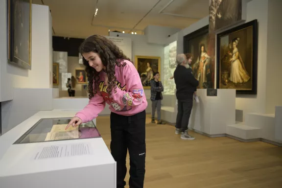 Een kind leest over het koninklijke huis in de tentoonstelling: De Oranjes