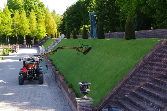 Een grasmaaier maait het schuine gras in de ondertuin