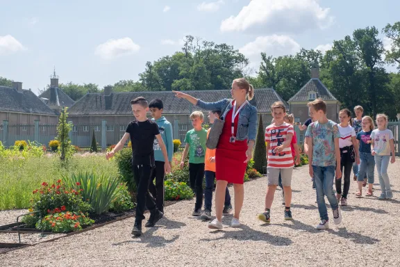 Museumeducator met leerlingen in de paleistuin.