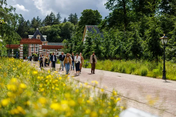 Docenten wandelen op de Stallenlaan richting het paleis.
