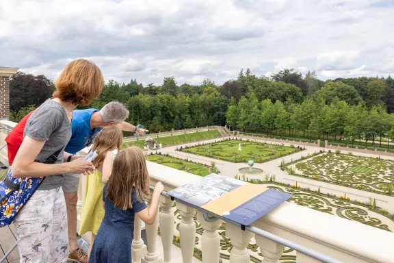 Bezoekers op het dak van Paleis Het Loo wijzend naar de baroktuin