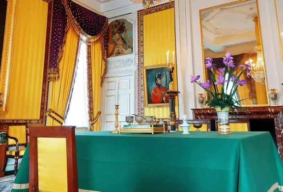 Historische kamer met geel behang en tafel met groen kleed