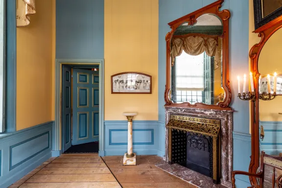 kamer met geel-blauwe muren, twee spiegels en openhaard