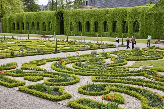 Die Menschen spazieren vom „Berceau“ aus zwischen den Frühlingsblumen im Barockgarten hindurch