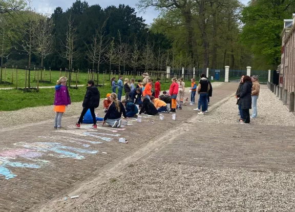 Kinderen versieren de stallenlaan met krijtjes
