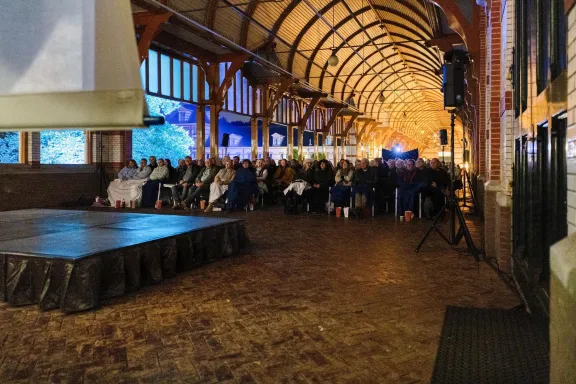 The stable yard with a screen and a group of people watching the film.