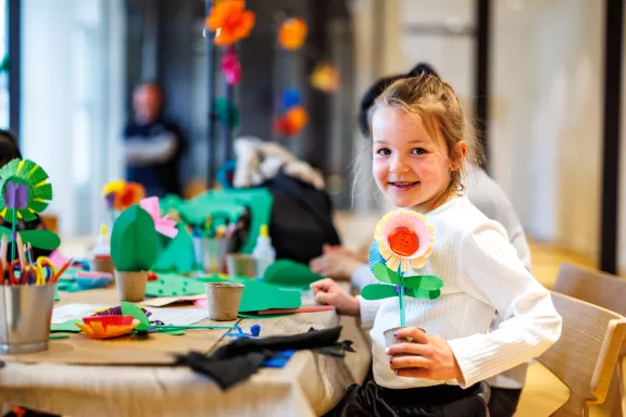 Een kind die in de zomer bloemen en insecten knutselt van papier