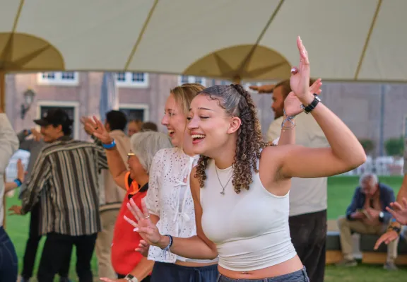 People dancing under a covered area on a lawn.