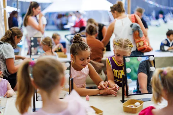 Een meisje verkleed als prinses en een cheerleader lakken hun nagels