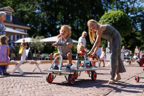 Ein Junge rast mit seinem Go-Kart über den Stallplatz, und seine Schwester schiebt ihn an