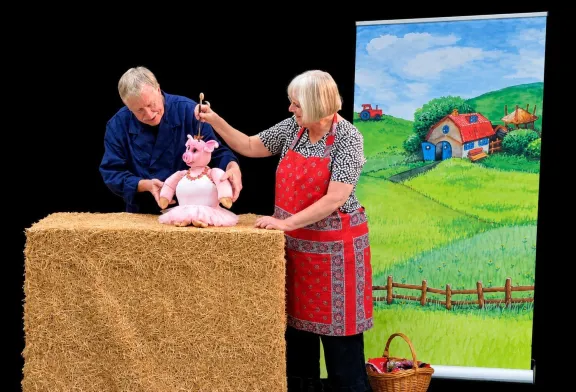 De poppenkast Bertus en de Bij-zondere Boom met Emma van Dobben, een man een varkenpop op een hooibaal en een boerderij op de achtergrond