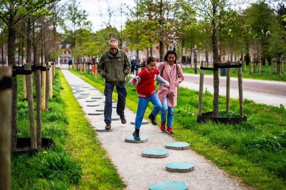 Een familie gaat over de XL hindernisbaan op de stallenlaan van het paleis richting het stallenplein