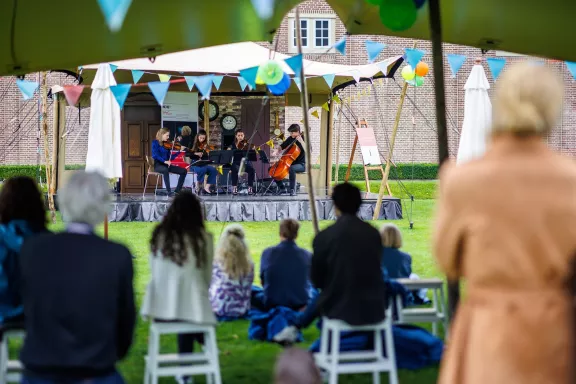 Mensen die snaarinstrumenten spelen in de paleistuinen tijdens de zomerconcerten