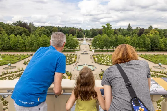 Bezoekers op het dak van Paleis Het Loo wijzend naar de baroktuin