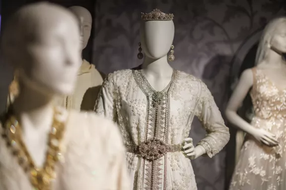 Een witte trouwjurk met zilveren ornamenten: een riem, oorbellen en een tiara