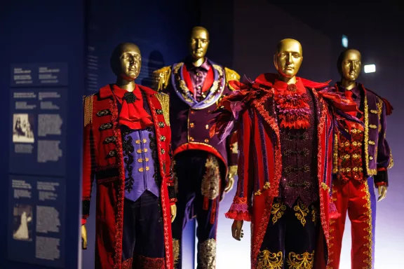 Vier kostuums gedragen door de Toppers in rood, paars, blauw en goud
