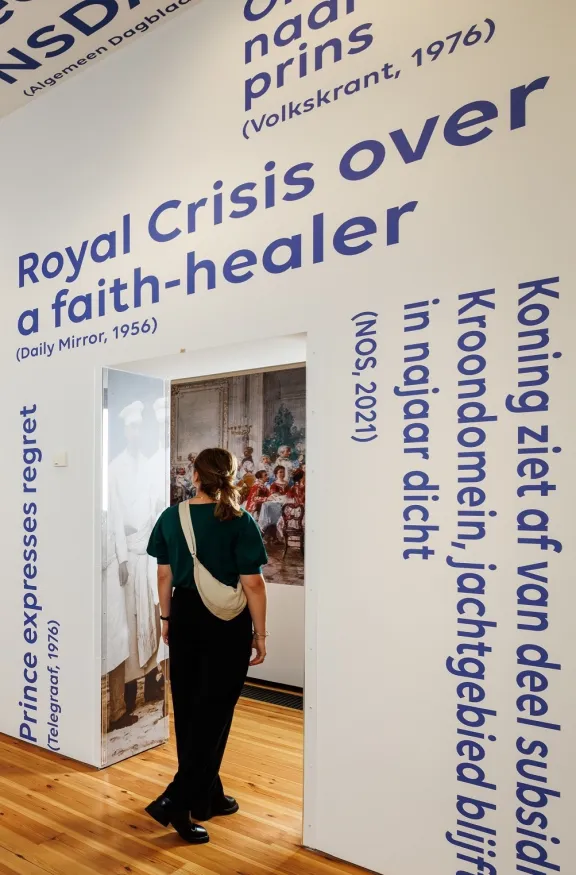 Student loopt door tentoonstellingszaal met krantenkoppen op de muur.