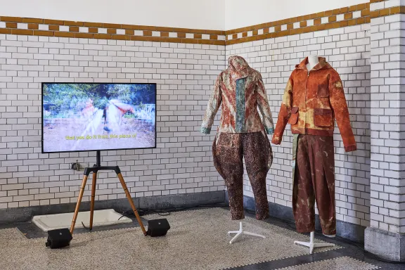 Twee paspoppen met kleding naast een tv scherm