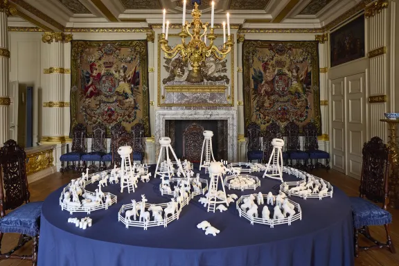 Blue table featuring clay animals, enclosed by fences and towers.