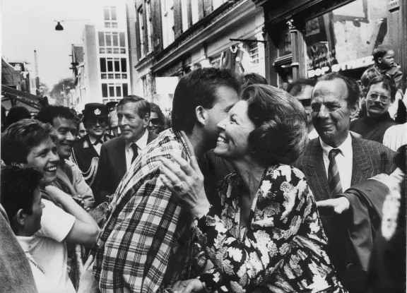 Een man kust Beatrix tijdens een spontaan bezoek van koningin Beatrix aan de rommelmarkt op Koninginnedag in de Jordaan, 1988