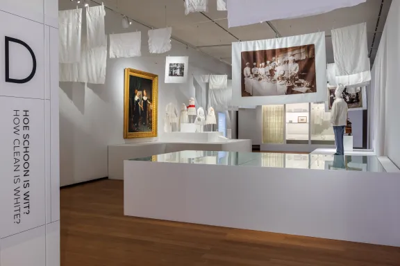 Overzichtsfoto tentoonstelling Wit, meer dan een kleur, met objecten, doeken hangend aan een waslijn en grote witte vitrines