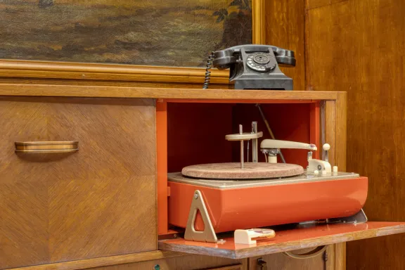 A record player and an old-fashioned telephone on top of/inside a wooden cupboard