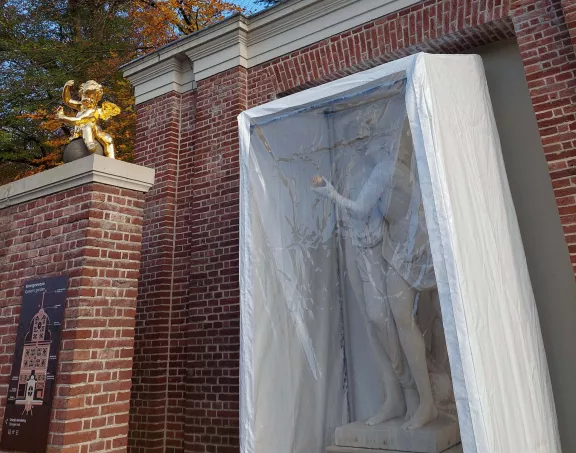 Standbeelden van Paris en Aphrodite met een plastic hoes er omheen in de koninginnetuin