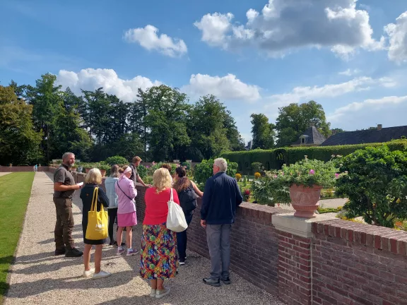 Een groep bezoekers krijgt een rondleiding door de tuin van Paleis Het Loo