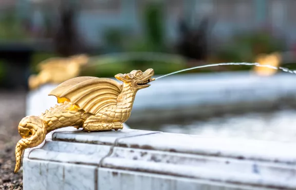 Een gouden draak spuwt water in de fontein van de paleistuin